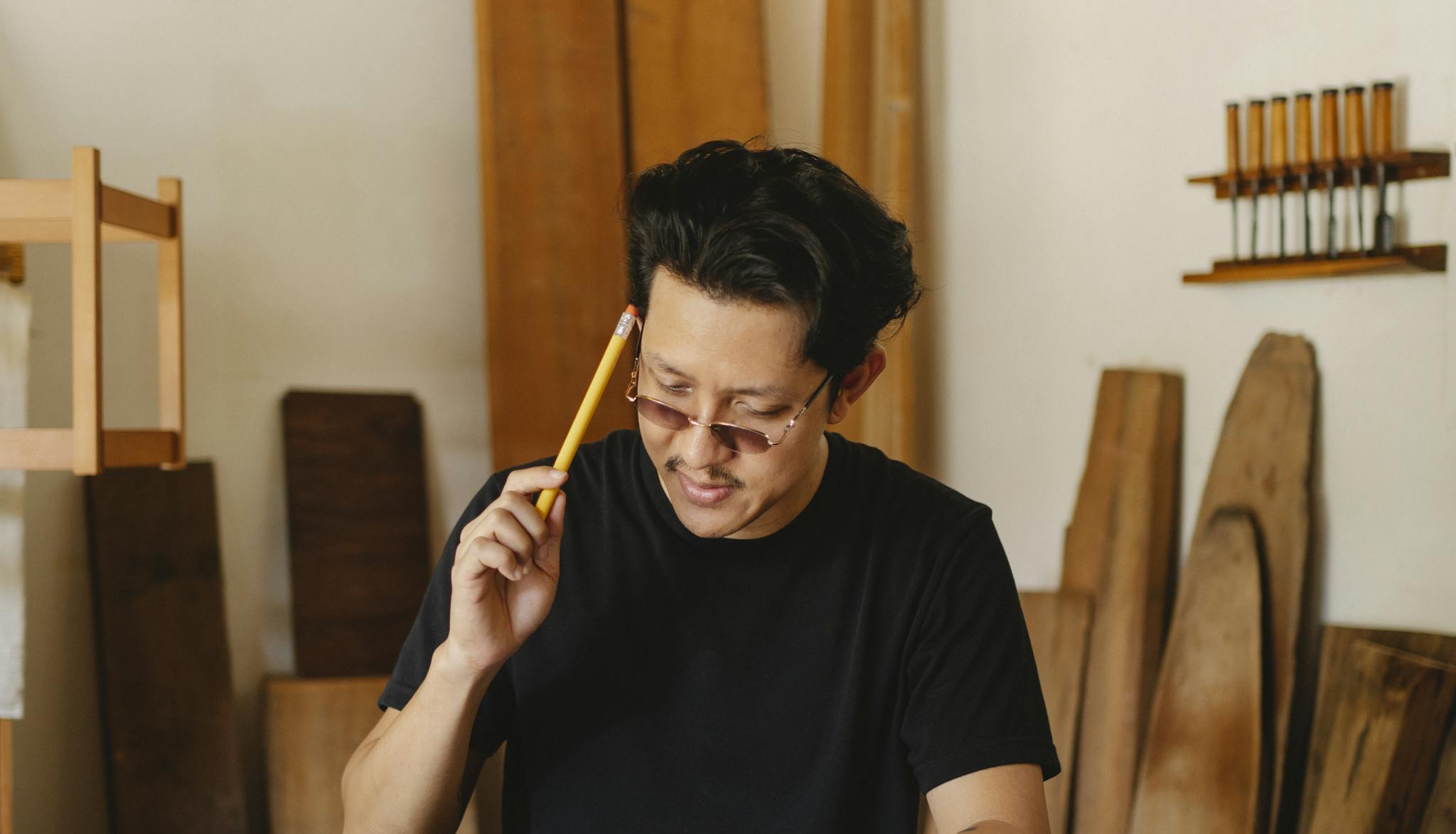 An artisan craftsman focuses on a woodworking project in his workshop.